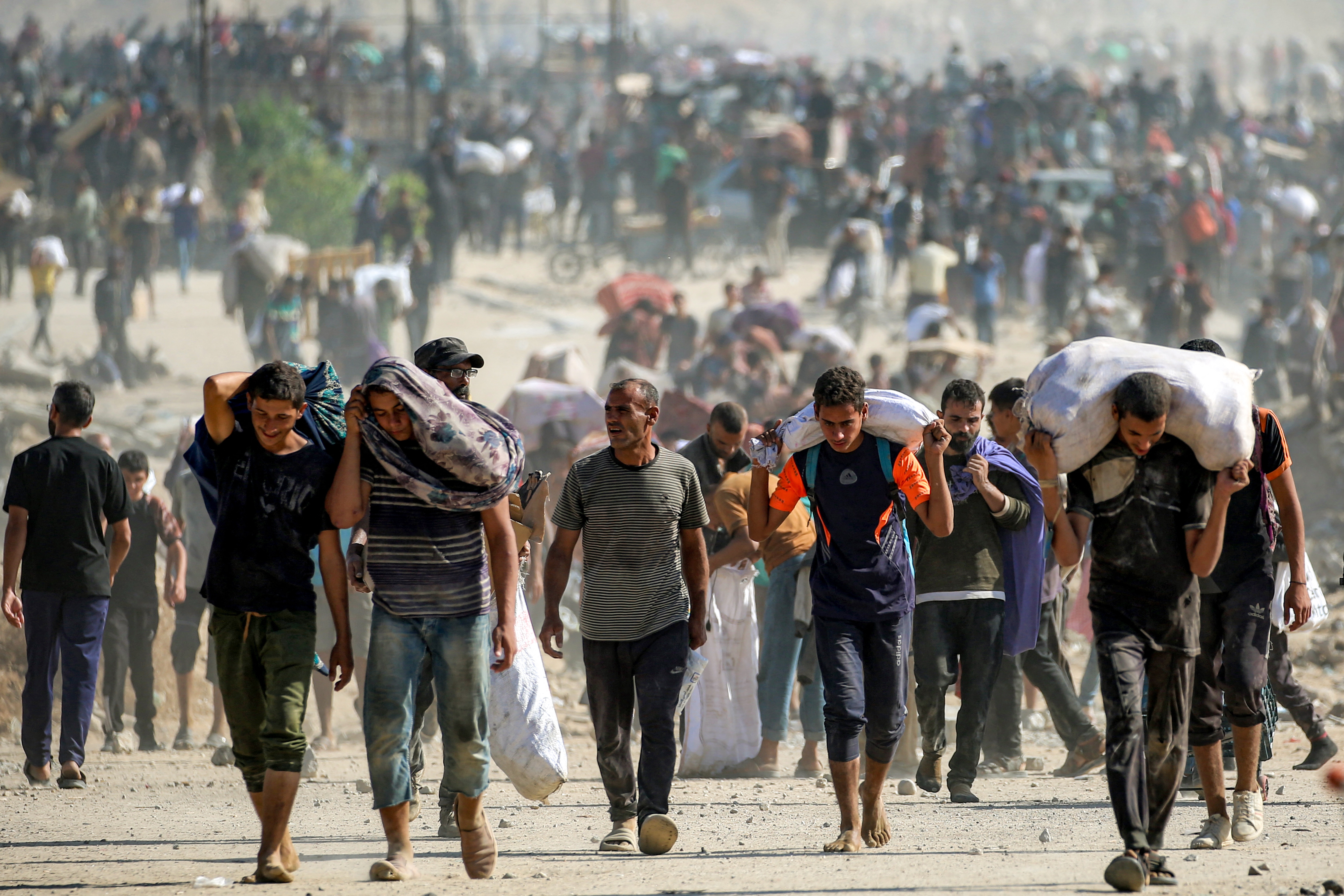 People walk with humanitarian aid packages that they received from a distribution center in Nuseirat in the central Gaza Strip, on Tuesday.